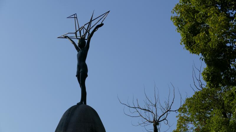 Na szczycie Pomnika postać dziewczynki – Sasaki Sadato – z ogromnym  żurawiem orgiami, symbolem  długowieczności
